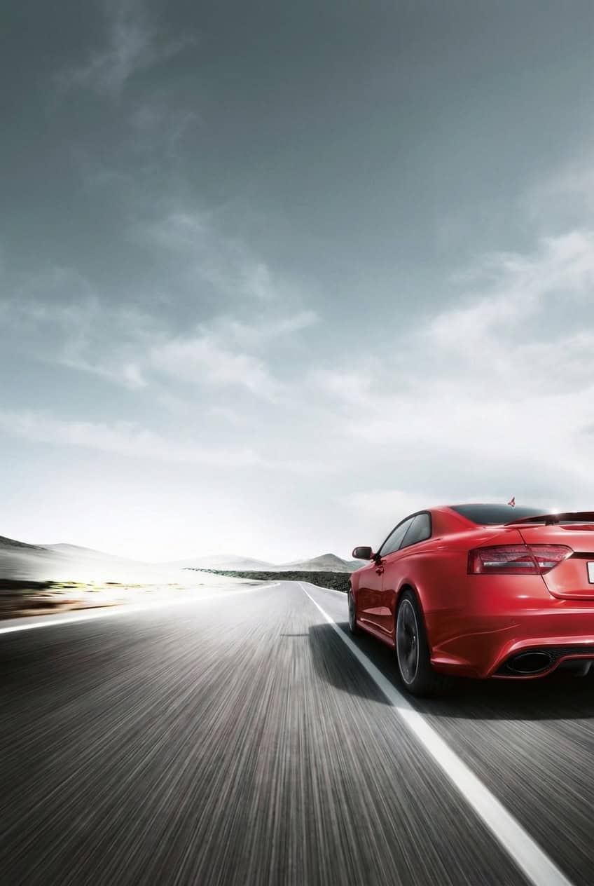 Red sports car on open road during daytime, vehicle testing at Vu & Vu Smog Check Center.